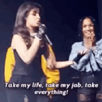 a woman is singing into a microphone while another woman stands behind her and says take my life take my job take everything !