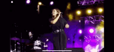 a woman is singing into a microphone on stage .