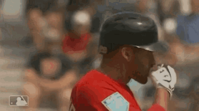 a baseball player is wearing a helmet and gloves while standing on a field .