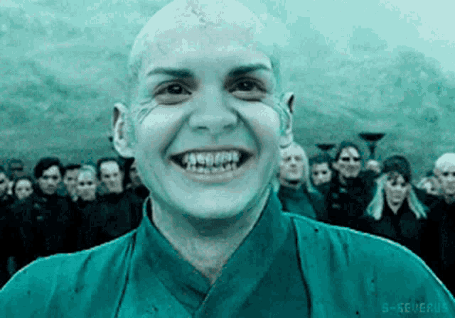 a man with a shaved head is smiling in front of a crowd with the letters g-severus visible