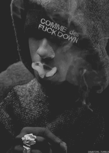 a man wearing a comme des fuck down beanie smoking a cigarette