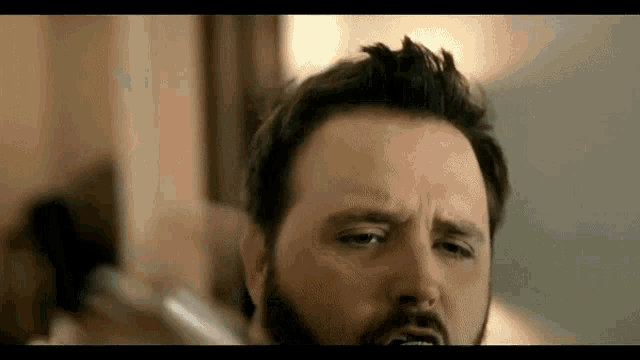 a man with a beard is brushing his teeth with a toothbrush in front of a mirror .