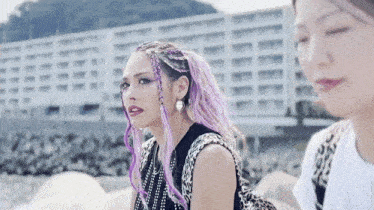 a woman with purple braids is standing next to another woman with her eyes closed