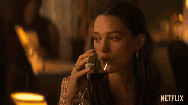 a woman drinking from a glass with netflix written on the bottom