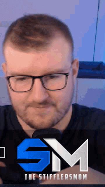 a man wearing glasses and a black shirt with the sm logo on the bottom