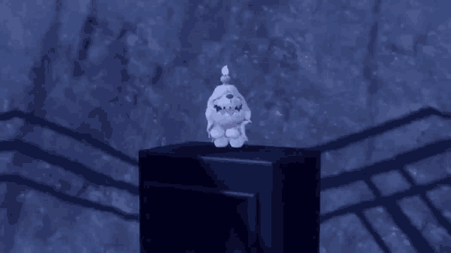 a stuffed animal with a candle on its head is sitting on top of a box .