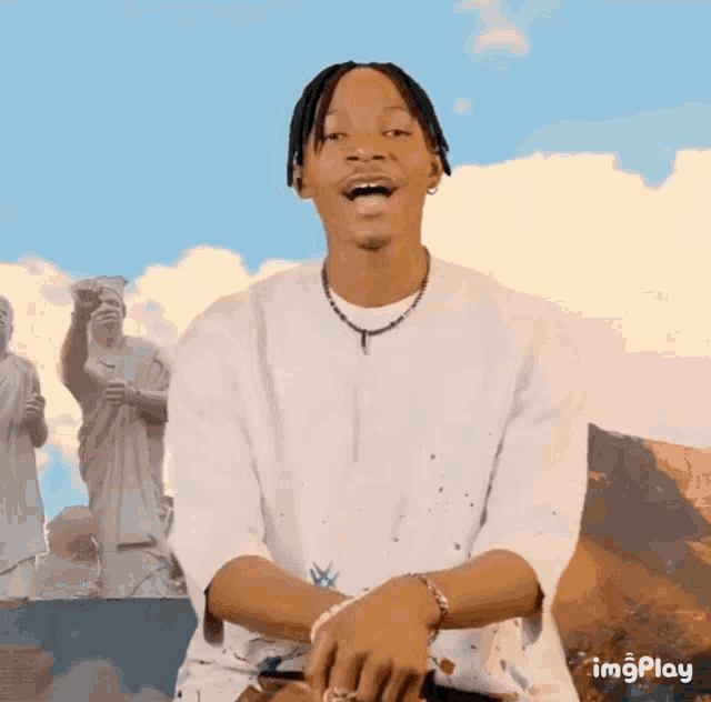 a man in a white shirt is laughing in front of a collage of statues