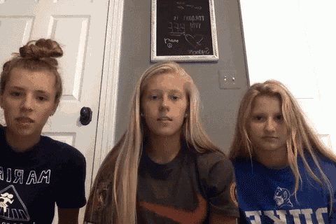 three girls are standing next to each other in front of a chalkboard that says " i am "