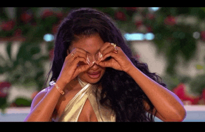 a woman in a gold dress is covering her eyes with her hands while crying .