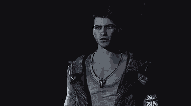 a man is standing in the dark wearing a necklace .