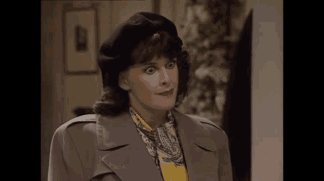 a woman wearing a trench coat and a beret is making a funny face .