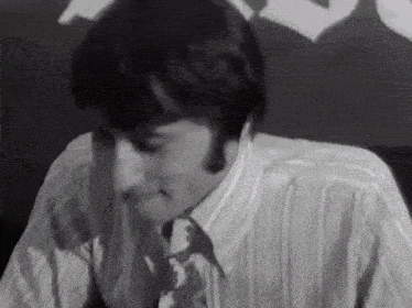 a black and white photo of a man in a striped shirt and tie