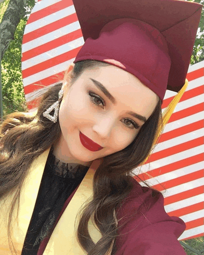 a woman wearing a graduation cap and gown poses for a picture