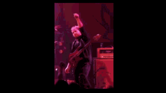 a man is playing a guitar on a stage in front of a purple background .