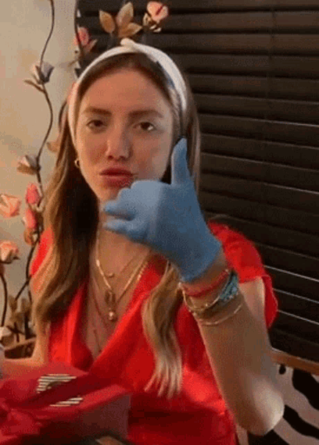 a woman wearing a headband and blue gloves is giving a thumbs up sign .