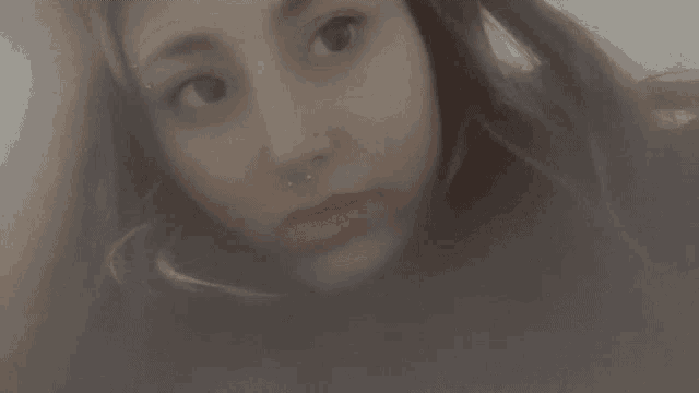 a woman with a nose ring is smiling for the camera .