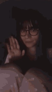 a woman wearing glasses is laying in a bed with her eyes closed .