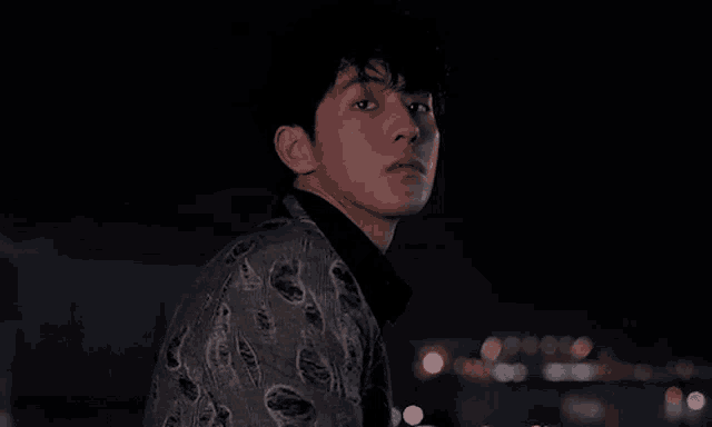 a young man with red hair is looking at the camera in the dark .