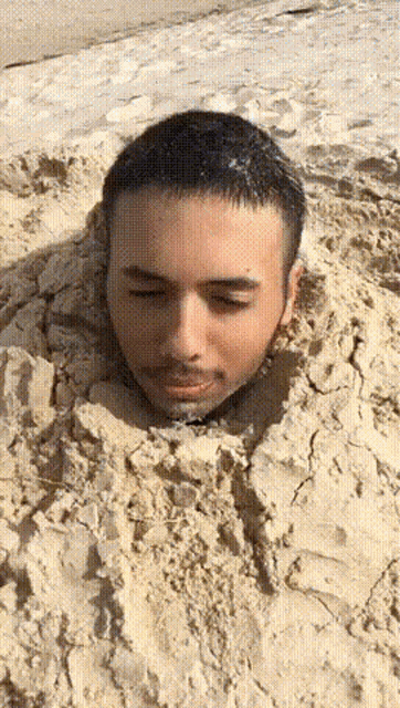 a man 's head is buried in a pile of sand