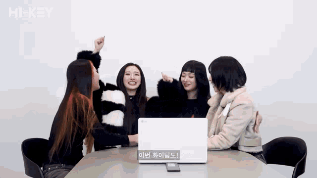 a group of girls are sitting around a table with a laptop and the word hi-key on the bottom