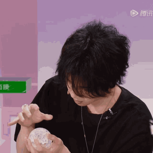 a person holding a clear ball in front of a pink background with chinese characters