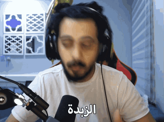 a man wearing headphones talks into a microphone with arabic writing