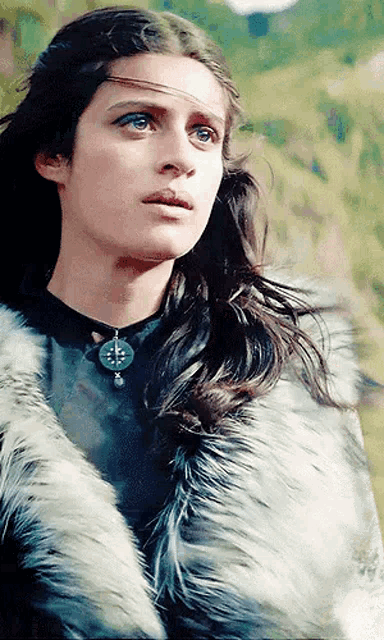 a woman wearing a fur coat and a necklace with a cross on it