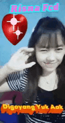 a girl in a striped shirt is smiling with a red heart in the background