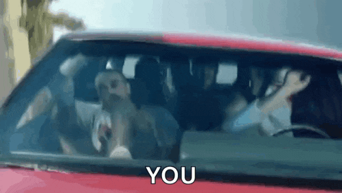 a group of people are sitting in a car with the words `` you '' written on the windshield .