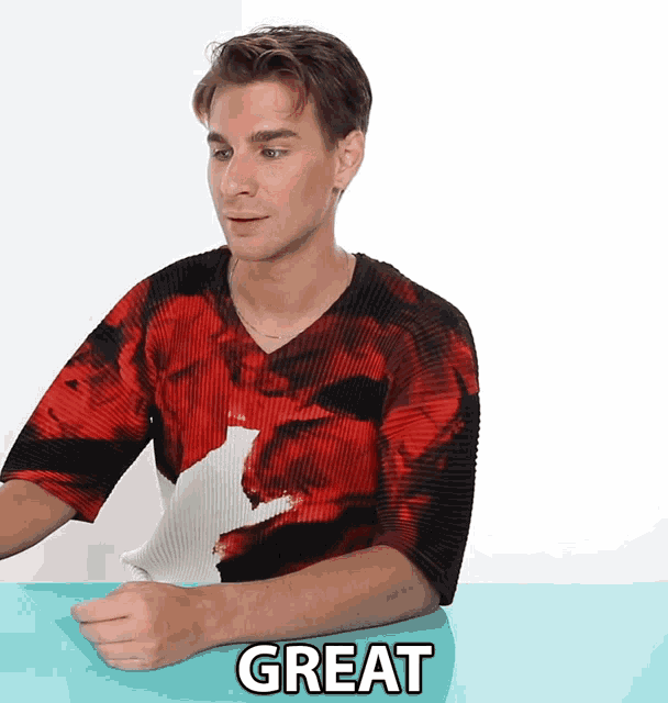 a man wearing a red and black shirt with the word great on the table