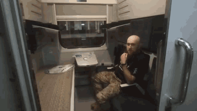 a man sits in a small room with a table and a sign that says visa on it