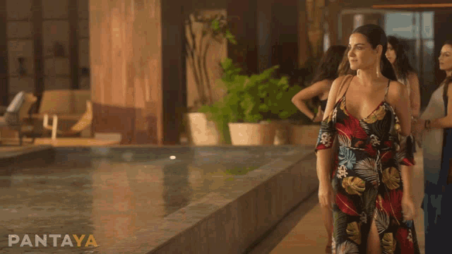 a woman in a floral dress stands in front of a swimming pool with pantaya written on the bottom