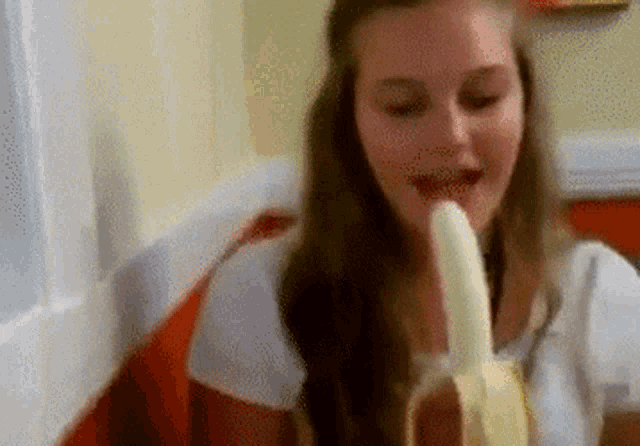 a girl is eating a banana with her mouth