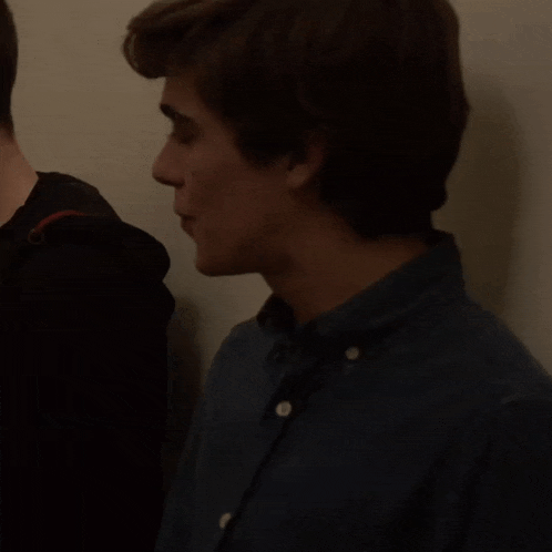a man in a denim shirt is smiling and talking to another man
