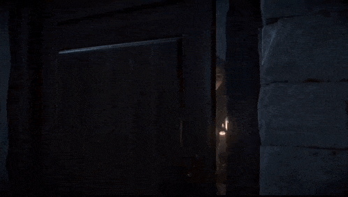 a woman wearing glasses and holding a candle is standing in a doorway .