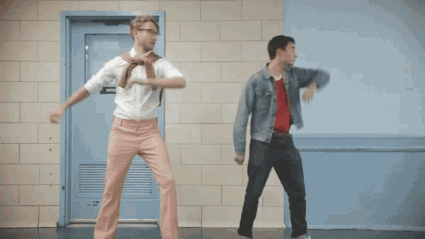 two men are dancing in front of a door labeled kitchen