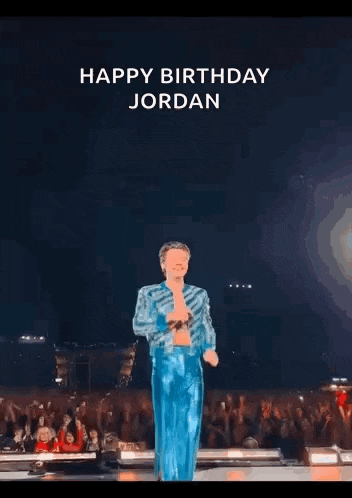 harry styles is standing on a stage in front of a crowd holding a microphone and singing .