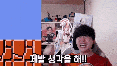 a man is sitting in front of a screen with korean writing on it and laughing .