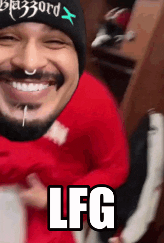 a man with a beard wearing a beanie and a red sweater is smiling and says lfg