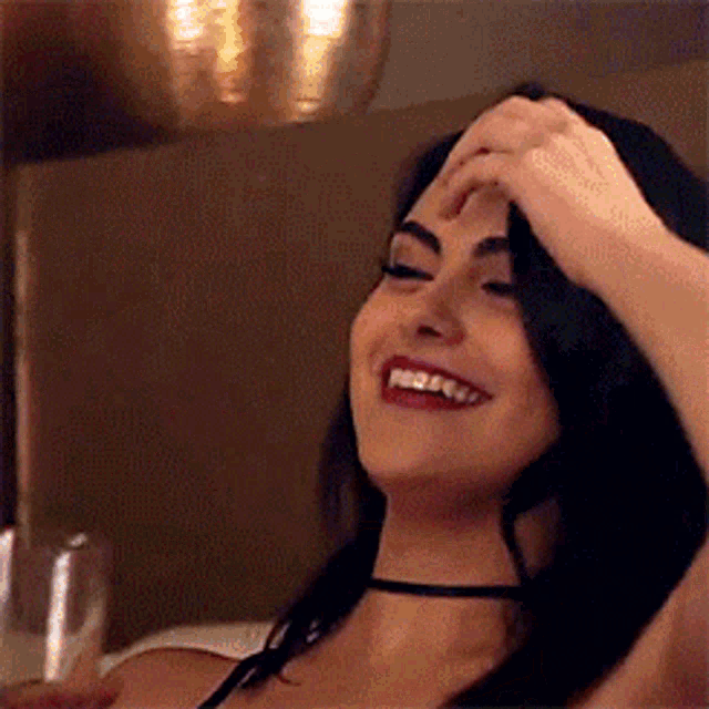 a woman is smiling while holding a glass of wine .