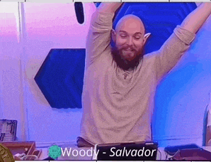a bald man with a beard is sitting in front of a laptop with his arms in the air .