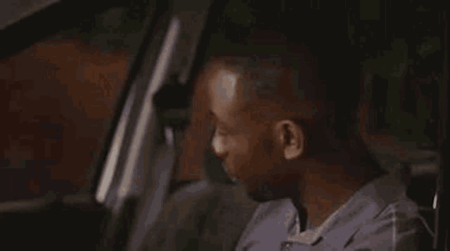 a man is sitting in the driver 's seat of a car looking out the window .