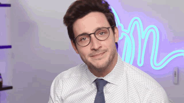 a man wearing glasses and a tie looks at the camera