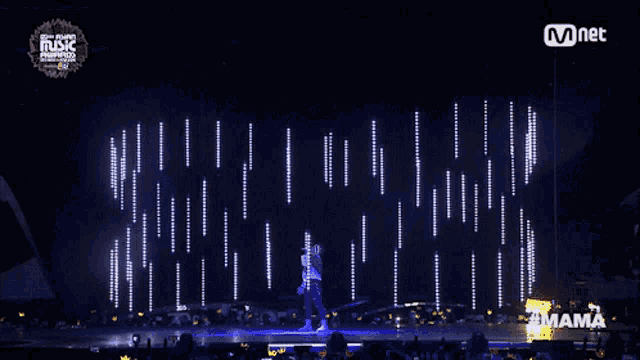 a man stands on a stage with a mnet logo on the bottom