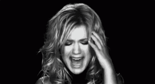 a black and white photo of a woman covering her face with her hands and screaming .