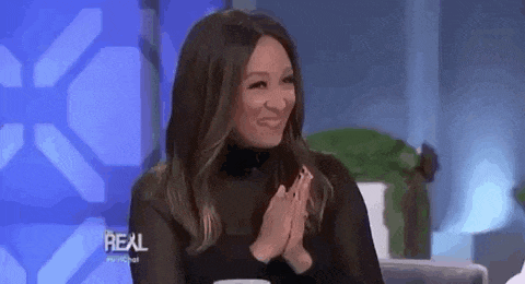a woman is sitting on a stage with her hands folded and smiling .