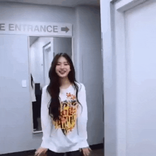 a woman is standing in a hallway in front of a sign that says entrance .
