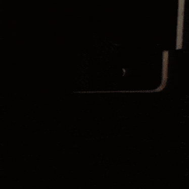 a man in a striped shirt is standing in front of a microwave .