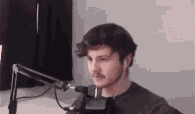 a man is sitting in front of a microphone .