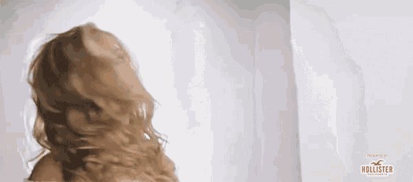 a woman is standing in front of a white wall with a hollister logo on it